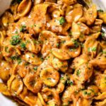 One-pot French onion pasta in a Dutch oven topped with melted gruyere cheese and fresh parsley