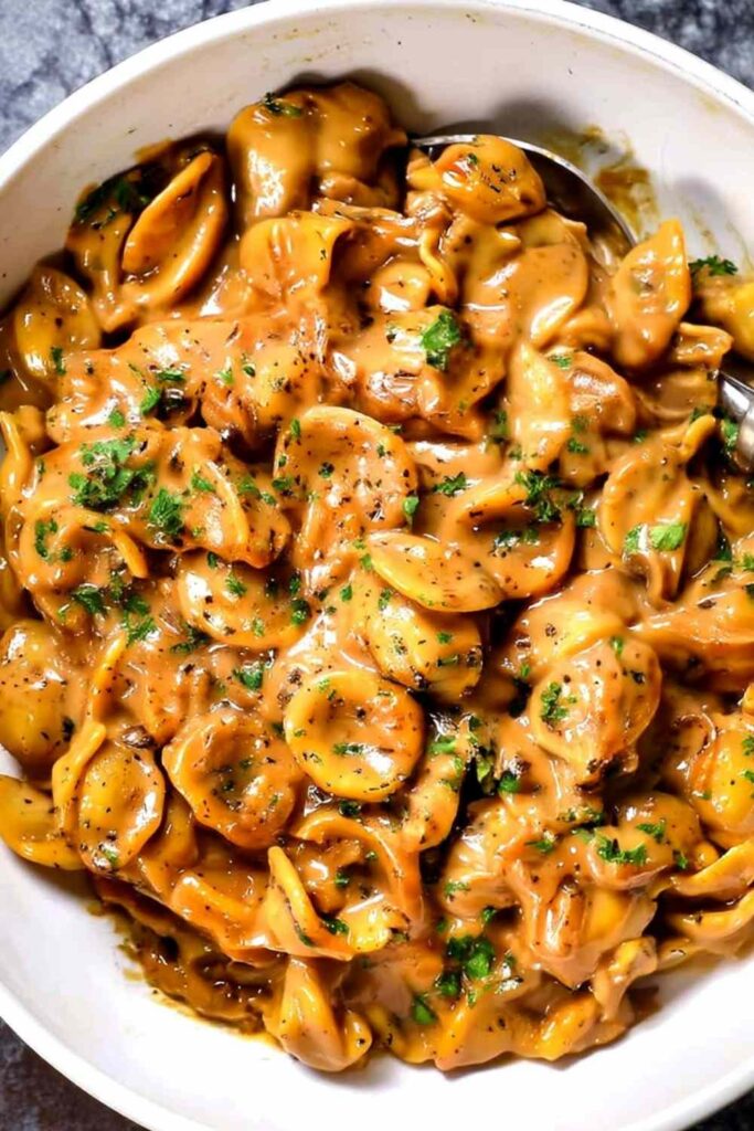 One-pot French onion pasta in a Dutch oven topped with melted gruyere cheese and fresh parsley
