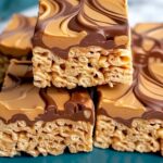 Peanut butter Rice Krispie treats stacked on white plate showing gooey texture