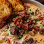 Philly Cheesesteak Soup in white bowl topped with crispy bacon and served with cheesy toast