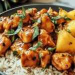 Pineapple chicken and rice in a large skillet with golden chicken pieces, pineapple chunks, and fluffy rice garnished with green onions