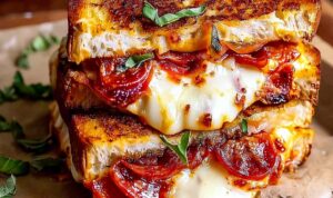 Pizza grilled cheese sandwich cut in half showing melted mozzarella and pepperoni filling