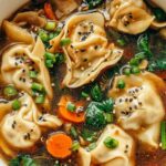 Bowl of potsticker soup with dumplings, spinach, green onions and sesame seeds in aromatic broth