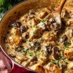 Creamy chicken stroganoff with mushrooms served over egg noodles on white plate