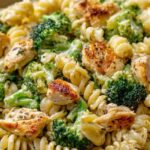 Rotisserie Chicken Broccoli Pasta in white bowl with fork showing creamy sauce coating pasta and bright green broccoli