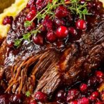 Slow-braised beef roast with cranberry balsamic glaze on white platter with fresh thyme garnish