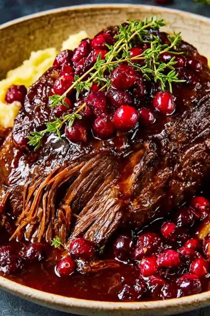 Slow-braised beef roast with cranberry balsamic glaze on white platter with fresh thyme garnish