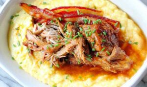 Sliced slow cooker apple butter glazed pork tenderloin on white platter with glaze drizzled on top