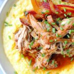 Sliced slow cooker apple butter glazed pork tenderloin on white platter with glaze drizzled on top