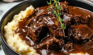 Slow Cooker Beef Manhattan served on white plate with shredded beef over mashed potatoes and toast covered in rich brown gravy