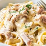 Slow Cooker Chicken Cordon Bleu Pasta in white bowl with creamy sauce and melted Swiss cheese