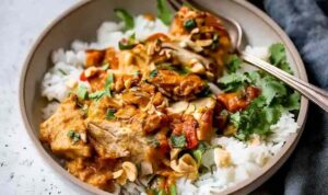 Slow Cooker Peanut Chicken in white bowl garnished with crushed peanuts and cilantro