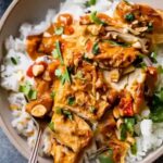 Slow Cooker Peanut Chicken in white bowl garnished with crushed peanuts and cilantro