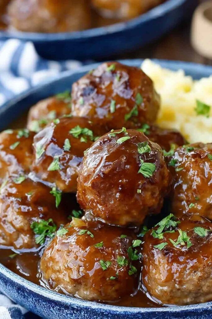 Slow cooker Salisbury steak meatballs in rich brown mushroom gravy served over creamy mashed potatoes