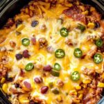 Slow cooker taco casserole with melted cheese topped with sour cream and cilantro