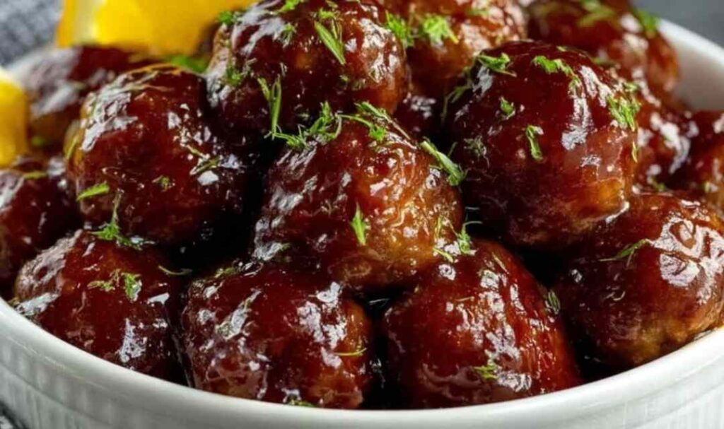 Slow cooker teriyaki meatballs garnished with sesame seeds and green onions in white bowl