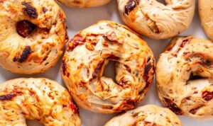 Sourdough bagels with sun-dried tomatoes and herbs on cooling rack with golden brown crust