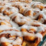 Sourdough cinnamon roll focaccia with white glaze drizzled on top in baking pan