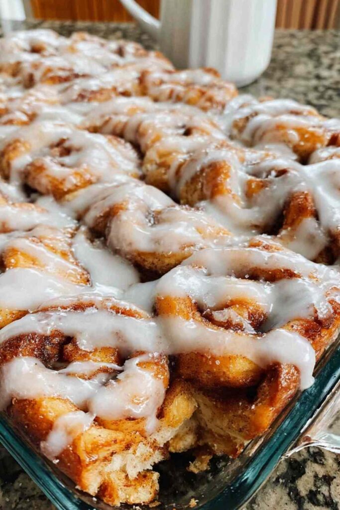 Sourdough cinnamon roll focaccia with white glaze drizzled on top in baking pan