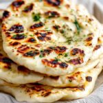 Soft fluffy sourdough discard naan with garlic butter on wooden board