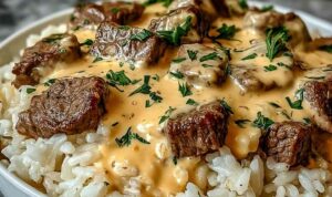Steak queso rice in a skillet with melted cheese, cilantro garnish, and jalapeño slices