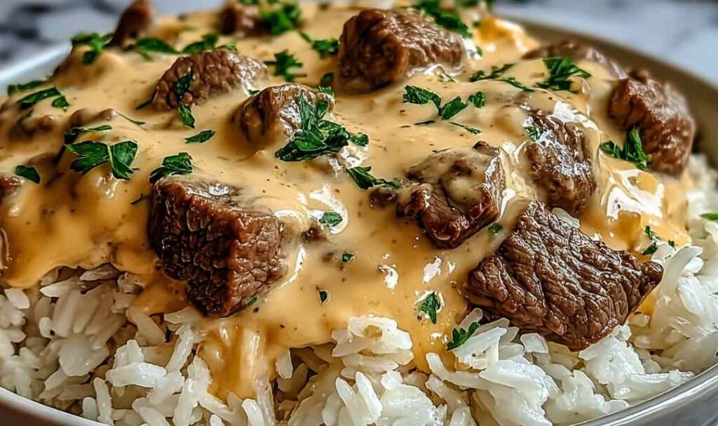 Steak queso rice in a skillet with melted cheese, cilantro garnish, and jalapeño slices