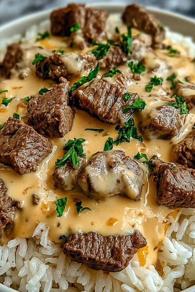 Steak queso rice in a skillet with melted cheese, cilantro garnish, and jalapeño slices