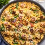 Tuscan chicken meatballs and orzo in creamy tomato sauce with spinach in a skillet