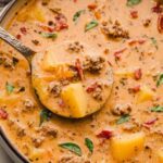 Tuscan sausage potato soup in white bowl with kale and parmesan cheese
