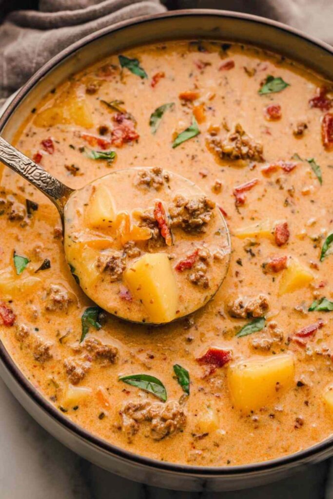 Tuscan sausage potato soup in white bowl with kale and parmesan cheese