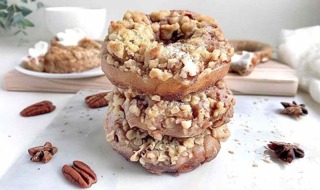 Vegan apple pecan streusel bagels on a white plate with pecan topping and apple filling