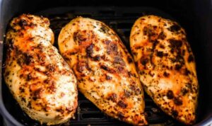 Juicy air fryer chicken breasts with golden crispy exterior on white plate