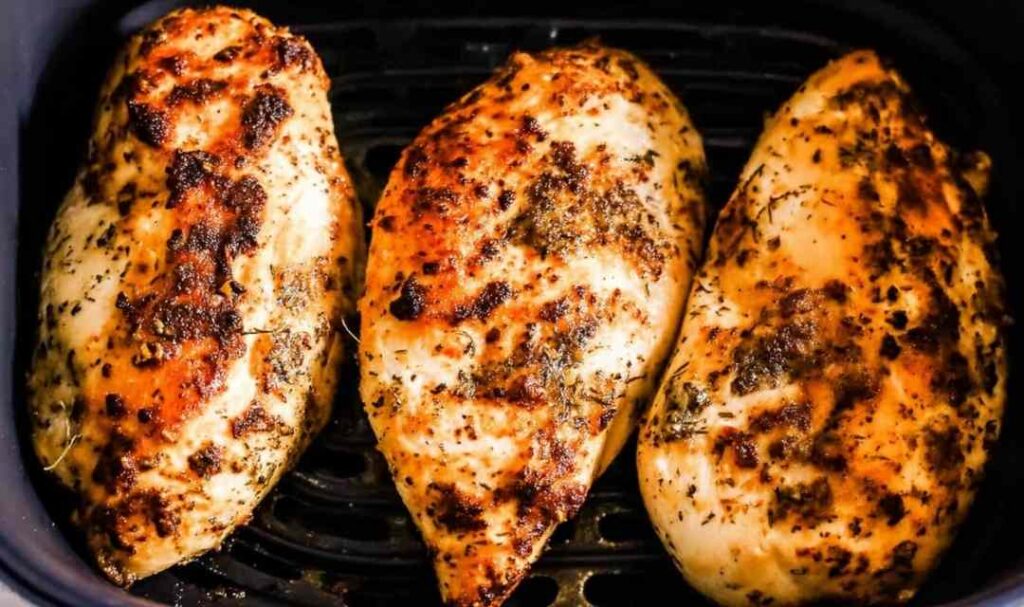 Juicy air fryer chicken breasts with golden crispy exterior on white plate
