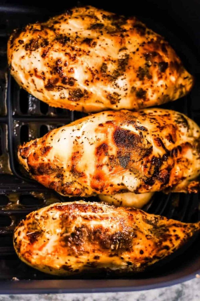Juicy air fryer chicken breasts with golden crispy exterior on white plate