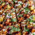BBQ chicken flatbread with melted cheese and cilantro on white plate