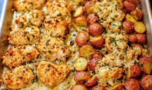 Baked Garlic Parmesan Chicken and Potatoes Baked garlic parmesan chicken and potatoes on a sheet pan with golden crispy edges and melted cheese