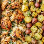 Baked garlic parmesan chicken and potatoes on a sheet pan with golden crispy edges and melted cheese