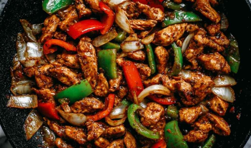 Black pepper chicken stir-fry in wok with vegetables and savory sauce
