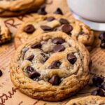 Brown butter sourdough discard chocolate chip cookies stacked on white plate with glass of milk