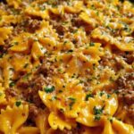Cajun Cream Cheese Alfredo Bowties with spiced ground beef served in a white bowl garnished with fresh parsley