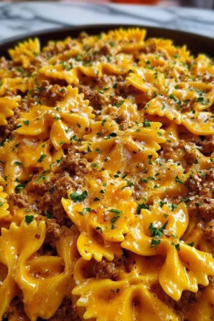 Cajun Cream Cheese Alfredo Bowties with spiced ground beef served in a white bowl garnished with fresh parsley