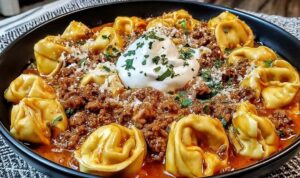 Cheesy beef enchilada tortellini in a skillet topped with melted Mexican cheese and fresh cilantro