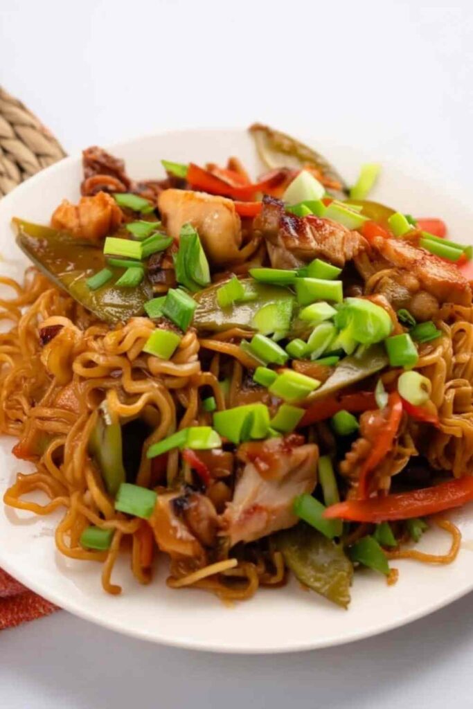 Chicken ramen stir fry in a wok with colorful vegetables and chopsticks