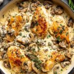 Golden chicken breasts in creamy white wine sauce with fresh thyme in a skillet