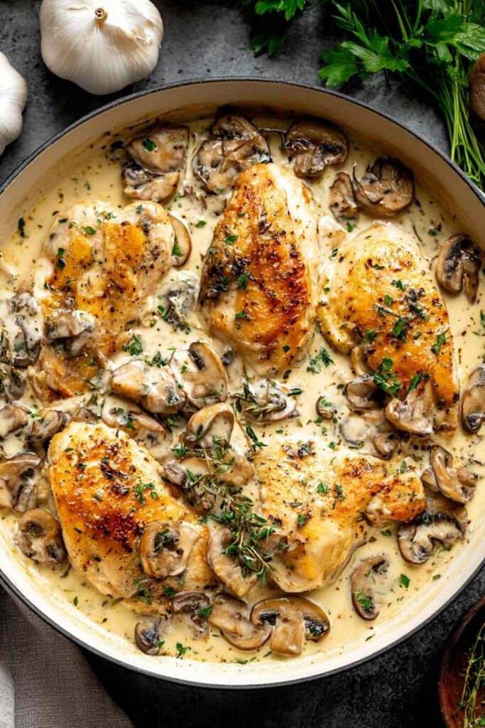 Golden chicken breasts in creamy white wine sauce with fresh thyme in a skillet