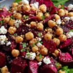 Chickpea beet and feta salad in white bowl with fresh herbs and lemon dressing