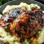 Chipotle honey chicken thighs with smoked gouda mashed potatoes on a white plate garnished with green beans