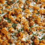 Cottage cheese protein pasta bake in white baking dish with melted mozzarella cheese and fresh basil garnish