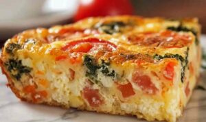 Cottage cheese veggie bake sliced in a white baking dish with golden top and colorful vegetables