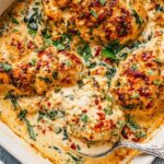 Creamy baked chicken breasts in skillet with garlic Parmesan sauce and fresh parsley garnish